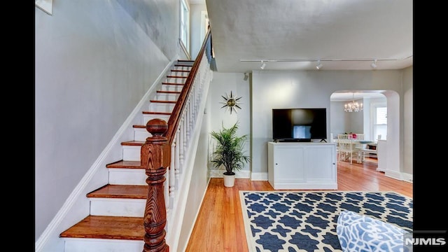 118 High St, Nutley, NJ 07110 - staircase featuring arched walkways, wood finished floors, a chandelier, and rail lighting