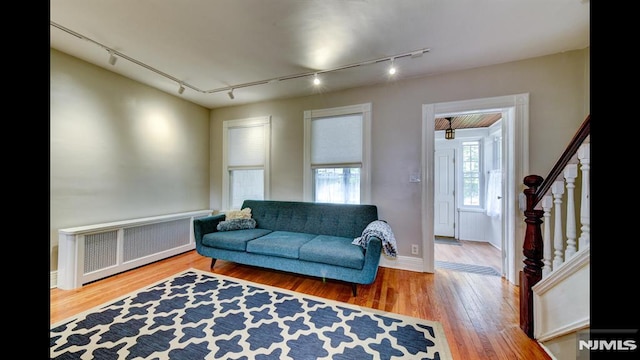 118 High St, Nutley, NJ 07110 - living room with radiator heating unit, rail lighting, wood finished floors, and stairs