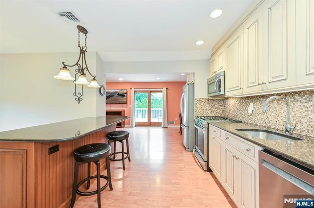 16 Murray Rd, Montvale, NJ 07645 - kitchen featuring stainless steel appliances, a kitchen breakfast bar, light wood-style floors, decorative backsplash, and hanging light fixtures