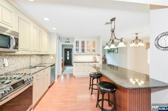 16 Murray Rd, Montvale, NJ 07645 - kitchen with appliances with stainless steel finishes, a kitchen breakfast bar, light wood-style floors, tasteful backsplash, and dark stone countertops