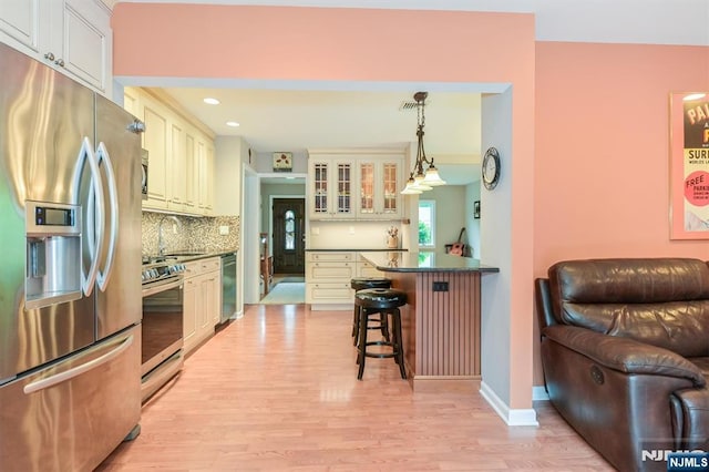16 Murray Rd, Montvale, NJ 07645 - kitchen featuring stainless steel appliances, dark countertops, a kitchen bar, light wood-style flooring, and backsplash