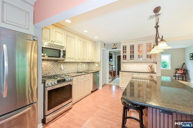 16 Murray Rd, Montvale, NJ 07645 - kitchen featuring stainless steel appliances, backsplash, cream cabinetry, glass insert cabinets, and light wood-type flooring