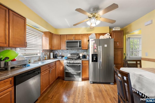 105 Old Hoboken Rd, Hackensack, NJ 07601 - kitchen featuring stainless steel appliances, light wood-style floors, backsplash, brown cabinetry, and a ceiling fan