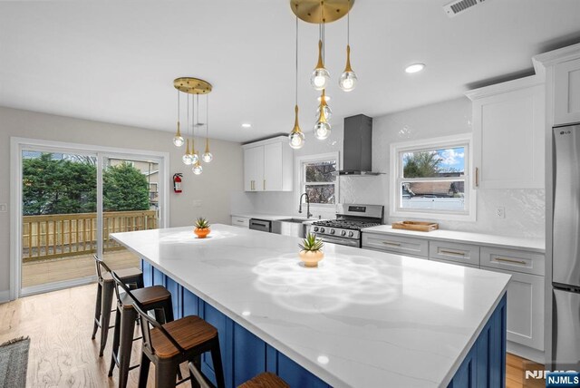 222 4th St, Ridgefield Park, NJ 07660 - kitchen with wall chimney range hood, stainless steel appliances, plenty of natural light, a kitchen bar, and recessed lighting