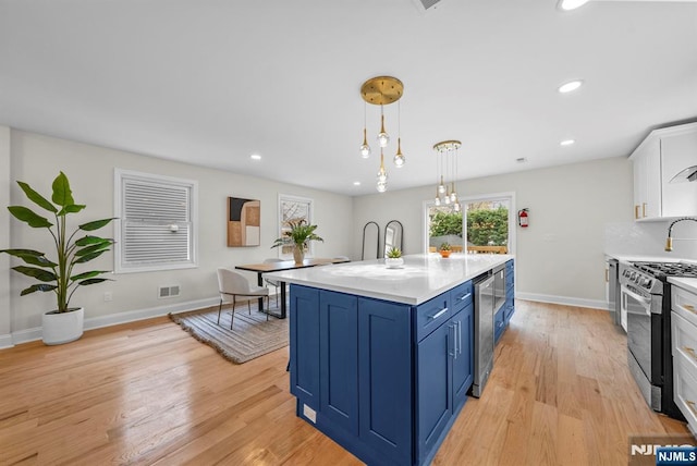 222 4th St, Ridgefield Park, NJ 07660 - kitchen with blue cabinetry, stainless steel gas range oven, light countertops, white cabinets, and light wood-style flooring