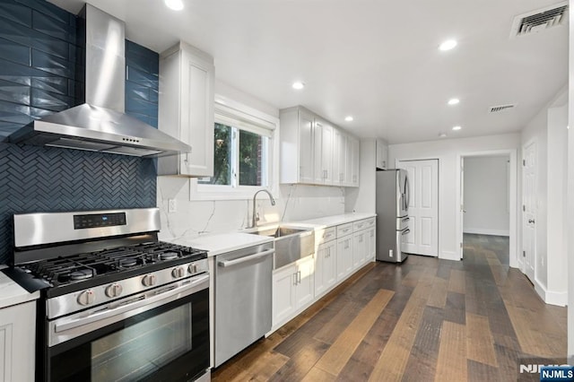 26 Amsterdam Ave, Teaneck, NJ 07666 - kitchen featuring appliances with stainless steel finishes, wall chimney exhaust hood, decorative backsplash, dark wood-style flooring, and light countertops