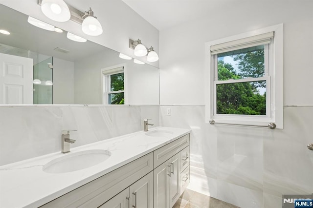 26 Amsterdam Ave, Teaneck, NJ 07666 - bathroom featuring tile walls, double vanity, tile patterned flooring, and wainscoting