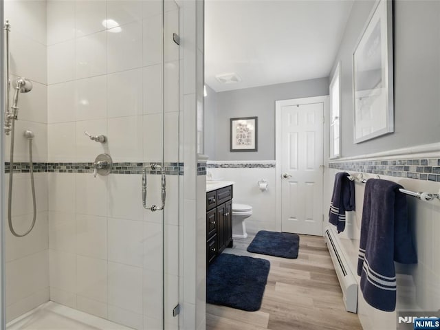 36 First, Hawthorne, NJ 07506 - bathroom featuring tile walls, a baseboard radiator, a shower stall, vanity, and wood finished floors