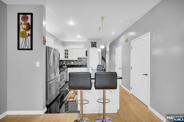 303 Wilshire Dr, Nutley, NJ 07110 - kitchen featuring stainless steel refrigerator with ice dispenser, light wood-style floors, white cabinets, glass insert cabinets, and a breakfast bar