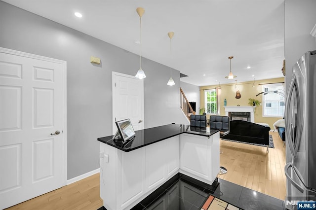 303 Wilshire Dr, Nutley, NJ 07110 - kitchen with freestanding refrigerator, dark countertops, open floor plan, a fireplace, and light wood finished floors