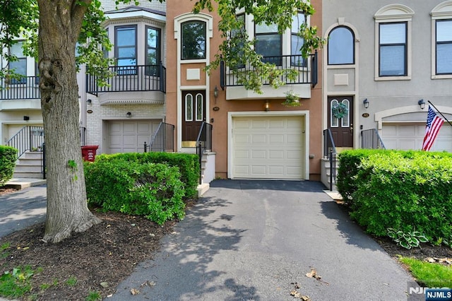 303 Wilshire Dr, Nutley, NJ 07110 - view of property with a garage, stucco siding, a balcony, and driveway