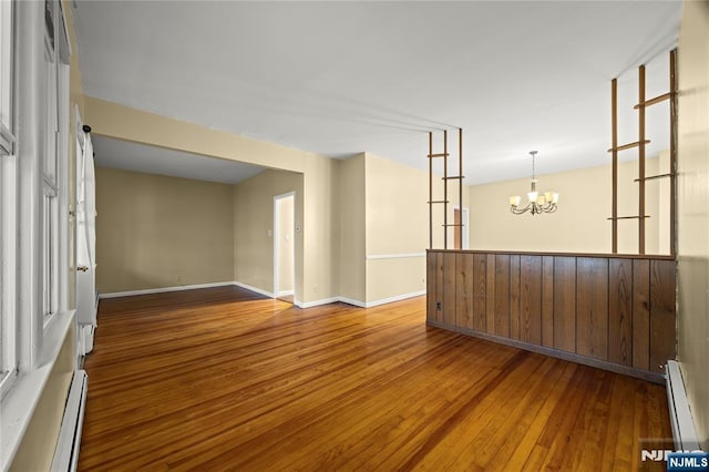 115 12th St, Prospect Park, NJ 07508 - empty room with baseboard heating, wood-type flooring, and a chandelier