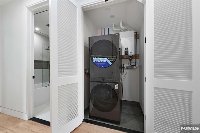 29 Armstrong Ave Unit 3, Jersey City, NJ 07305 - washroom featuring tankless water heater, stacked washer / drying machine, and wood finished floors