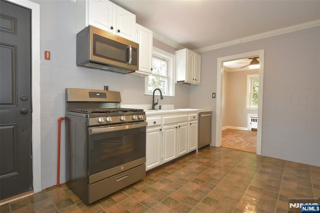 36 Grove St, Waldwick, NJ 07463 - kitchen with stainless steel appliances, white cabinetry, crown molding, stone finish floors, and light countertops