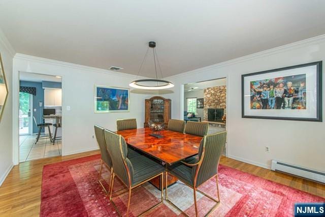 5 Hurley Ct, Wyckoff, NJ 07481 - dining area featuring baseboard heating, ornamental molding, light wood-style flooring, and a stone fireplace