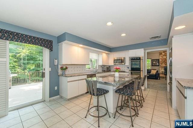 5 Hurley Ct, Wyckoff, NJ 07481 - kitchen with stainless steel appliances, a center island, white cabinets, light tile patterned floors, and tasteful backsplash