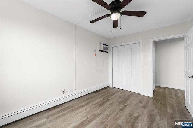 8829 Kennedy Blvd Unit E5, North Bergen, NJ 07047 - unfurnished bedroom featuring a baseboard radiator, wood finished floors, a closet, a wall unit AC, and a ceiling fan