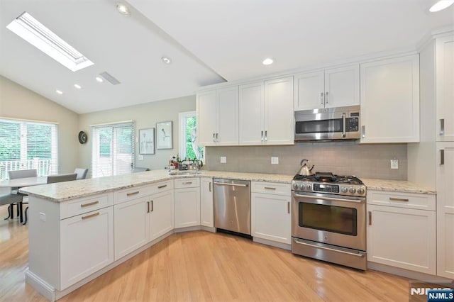 39 Terrace Rd, Wayne, NJ 07470 - kitchen featuring appliances with stainless steel finishes, a peninsula, white cabinets, lofted ceiling, and light wood finished floors