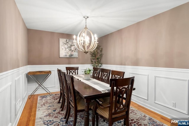 39 Division Ave, Hasbrouck Heights, NJ 07604 - dining area featuring a chandelier, wainscoting, light wood-type flooring, and a decorative wall