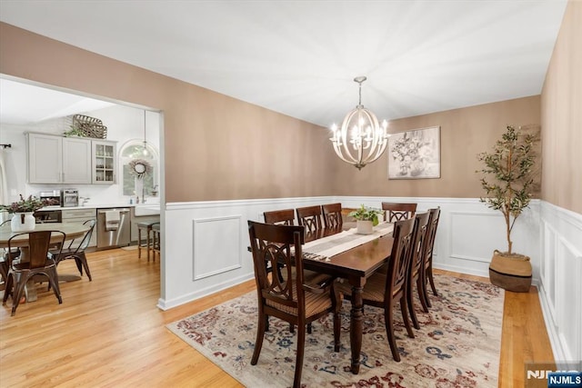 39 Division Ave, Hasbrouck Heights, NJ 07604 - dining area with a chandelier, wainscoting, light wood-style floors, and a decorative wall