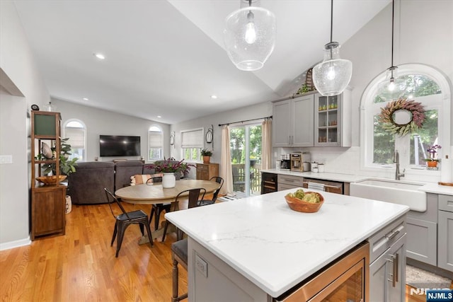 39 Division Ave, Hasbrouck Heights, NJ 07604 - kitchen featuring lofted ceiling, gray cabinets, light wood-type flooring, glass insert cabinets, and a center island