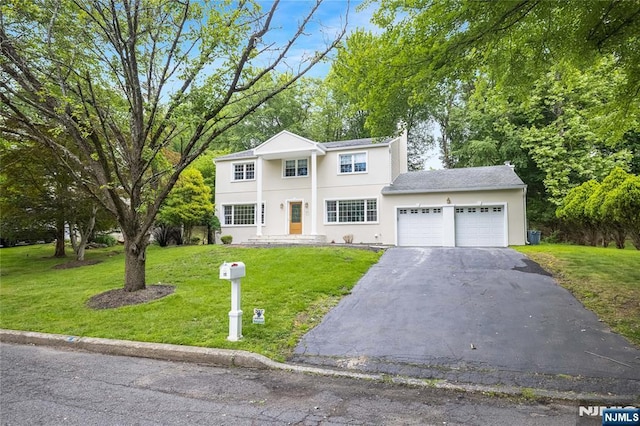 15 Kings Ct, Woodcliff Lake, NJ 07677 - view of front of home with a garage, asphalt driveway, a front lawn, and stucco siding