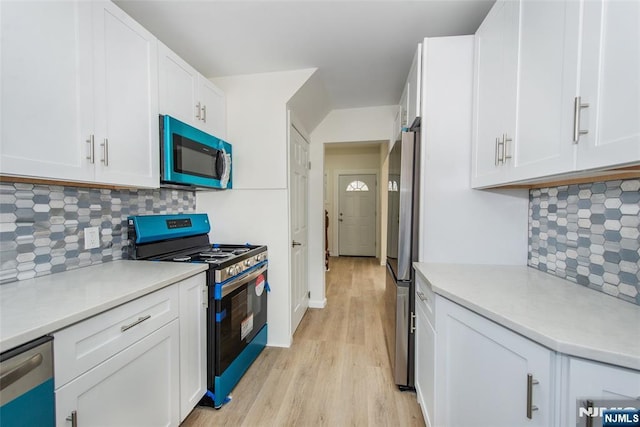 419 Central Ave, Haledon, NJ 07508 - kitchen with stainless steel appliances, light wood-style flooring, backsplash, and white cabinets