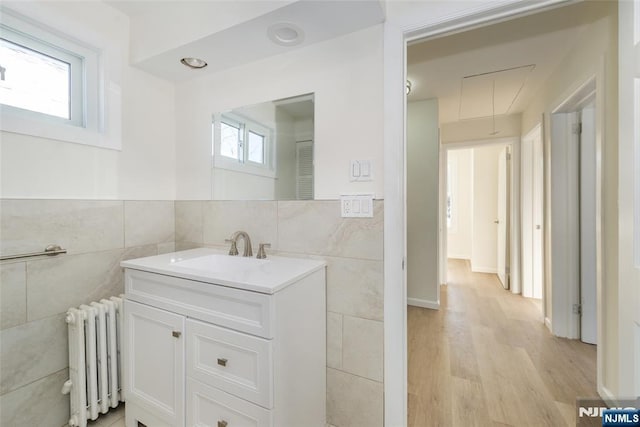 419 Central Ave, Haledon, NJ 07508 - bathroom with radiator, tile walls, vanity, wood finished floors, and a wainscoted wall