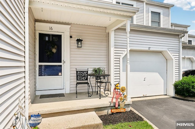 16 Iron Forge Vlg, Pompton Lakes, NJ 07442 - view of exterior entry featuring asphalt driveway, a garage, and covered porch