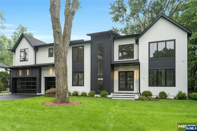 51 Harrison St, Haworth, NJ 07641 - view of front facade featuring stucco siding, an attached garage, french doors, and a front lawn