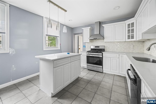683 E 28th St, Paterson, NJ 07504 - kitchen featuring wall chimney exhaust hood, stainless steel gas range oven, dishwashing machine, light tile patterned flooring, and light countertops