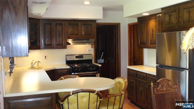 17 Gunther Ave, Lodi, NJ 07644 - kitchen with appliances with stainless steel finishes, under cabinet range hood, light countertops, dark brown cabinetry, and a peninsula