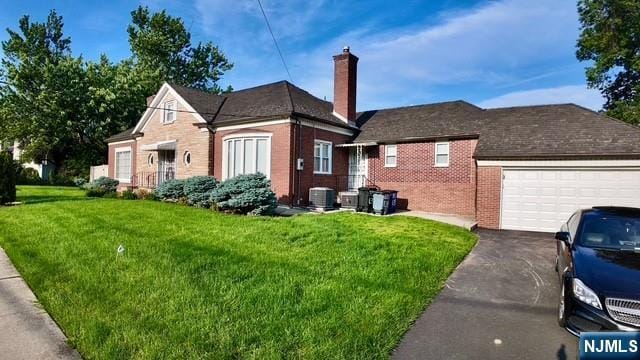 313-321 39th St, Paterson, NJ 07504 - view of side of property featuring brick siding, asphalt driveway, a yard, a garage, and a chimney