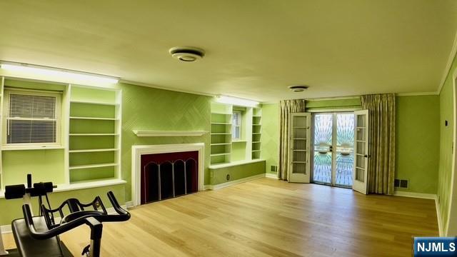 313-321 39th St, Paterson, NJ 07504 - unfurnished living room featuring a fireplace, wood finished floors, built in shelves, french doors, and ornamental molding