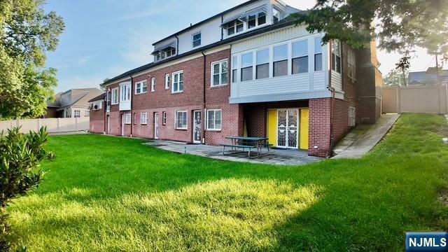 313-321 39th St, Paterson, NJ 07504 - back of property featuring brick siding, a patio, and a fenced backyard