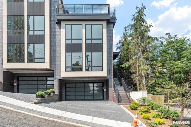 135 Old Palisade Rd, Fort Lee, NJ 07024 - contemporary home with stairway, an attached garage, asphalt driveway, brick siding, and stucco siding