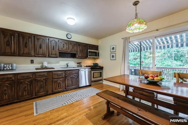 117 Morton Dr, Ramsey, NJ 07446 - kitchen featuring appliances with stainless steel finishes, light countertops, dark brown cabinets, decorative light fixtures, and light wood finished floors