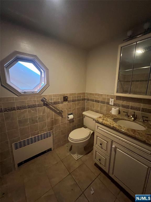 106 Prescott St, Demarest, NJ 07627 - bathroom featuring radiator, tile walls, tile patterned flooring, vanity, and a wainscoted wall