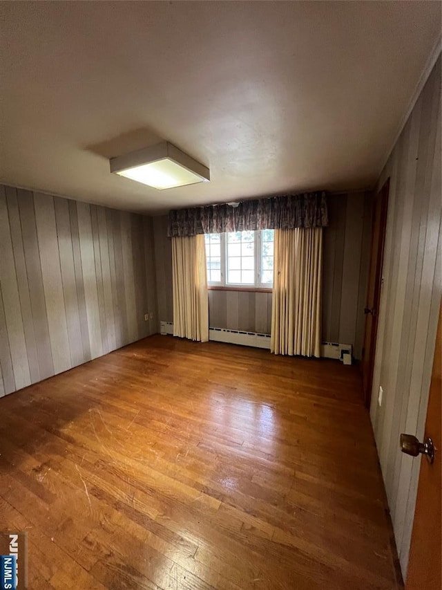 106 Prescott St, Demarest, NJ 07627 - unfurnished room with a baseboard radiator, hardwood / wood-style flooring, wooden walls, and a baseboard heating unit