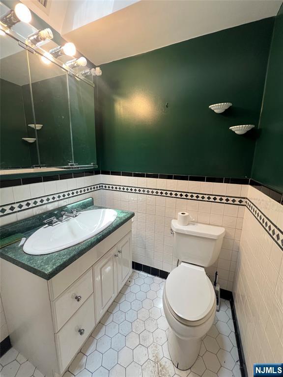 106 Prescott St, Demarest, NJ 07627 - bathroom featuring tile walls, vanity, wainscoting, and tile patterned floors