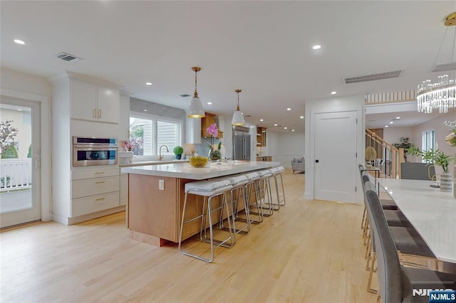 415 Bailey Rd, Paramus, NJ 07652 - kitchen with stainless steel oven, light wood-type flooring, a large island, light countertops, and white cabinetry