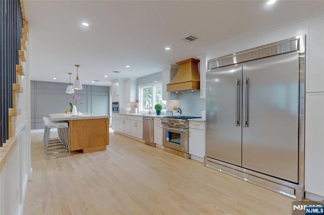 415 Bailey Rd, Paramus, NJ 07652 - kitchen featuring high end appliances, custom exhaust hood, light wood-style flooring, light countertops, and white cabinetry