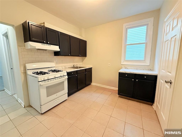 1 9th Ave, East Orange, NJ 07018 - kitchen with white gas stove, under cabinet range hood, backsplash, light countertops, and dark cabinetry