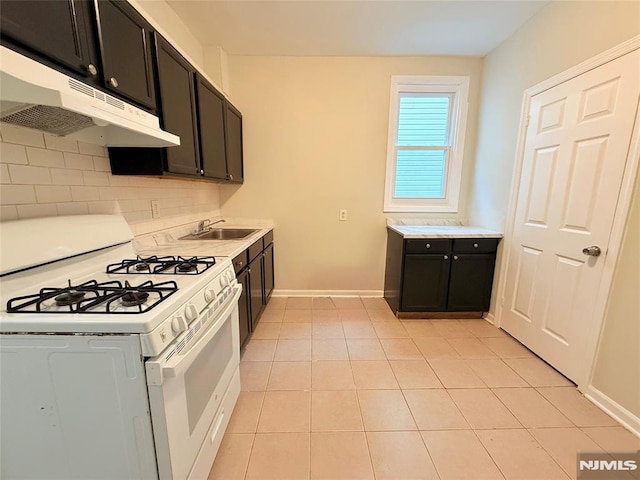 1 9th Ave, East Orange, NJ 07018 - kitchen with white gas stove, under cabinet range hood, backsplash, light tile patterned floors, and light countertops