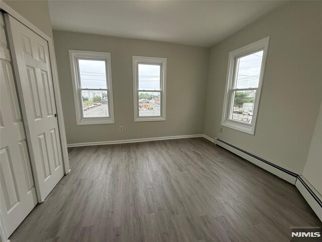 1 9th Ave, East Orange, NJ 07018 - unfurnished bedroom with a baseboard heating unit and wood finished floors