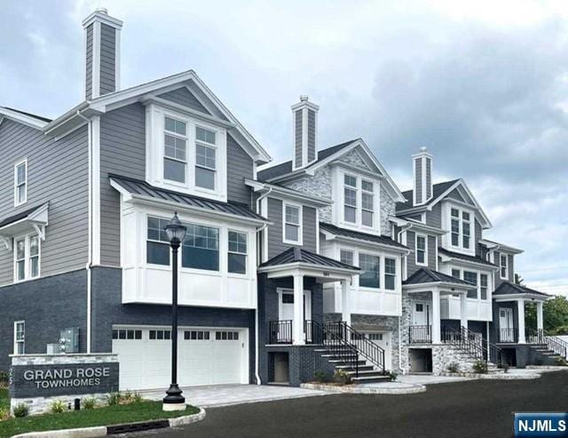 25 Division St Unit 403, Cresskill, NJ 07626 - view of front facade with a chimney, a standing seam roof, a metal roof, a garage, and asphalt driveway