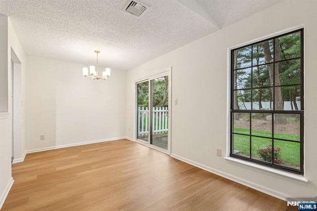 7 Eakens Ct, Mahwah, NJ 07430 - unfurnished room featuring a chandelier, light wood-type flooring, healthy amount of natural light, and a textured ceiling