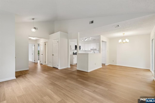 7 Eakens Ct, Mahwah, NJ 07430 - unfurnished living room with a chandelier, lofted ceiling, and light wood-style flooring
