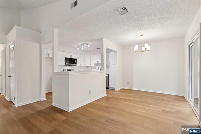 7 Eakens Ct, Mahwah, NJ 07430 - kitchen featuring stainless steel microwave, a chandelier, light wood-style floors, white cabinetry, and a textured ceiling