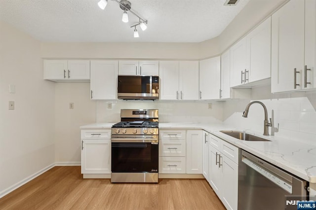 7 Eakens Ct, Mahwah, NJ 07430 - kitchen with stainless steel appliances, light wood finished floors, white cabinets, light stone counters, and a textured ceiling